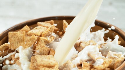 Breakfast cereals dropping into bowl with pouring milk