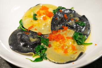yellow and black ravioli with caviar and spinach