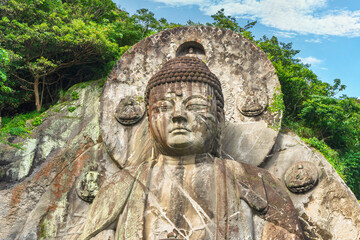 Obraz premium Close-up on the head of the largest stone-carved magaibutsu statue of giant buddha Daibutsu Yakushi of Nihonji temple on the mountain sides of Mount Nokogiri stone quarry.