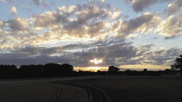 Paradoxical panorama of a nighttime rural landscape, lit by the sunset in cumulus sky. Aerial shot.