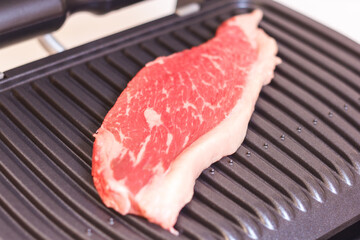 A piece of fresh meat. Juicy beef steak on the electric grill. - 368850219
