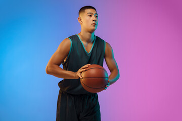 Handsome. Young basketball player confident posing with ball on gradient background in neon....