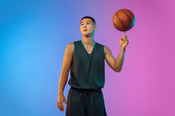 Handsome. Young basketball player confident posing with ball on gradient background in neon....