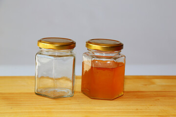 Glass jar filled with honey and empty jar. Glassware stands on a wooden table. Close-up view. Concept: different view,, different opinions,