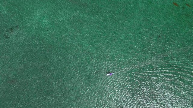 drone follows surfer on windsurf with sail going fast with his windsurf gear, sail, board over sea with nice wind on sunny day