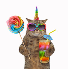 The beige cat unicorn in sunglasses  is holding a lollipop and a glass of rainbow juice with a straw drinking. White background. Isolated.