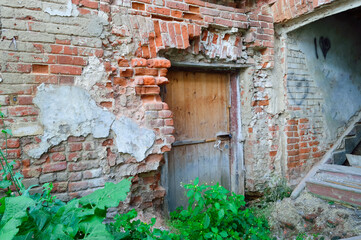 old wooden door in an old ruined house, closed with locks, a broken staircase without steps, ancient building