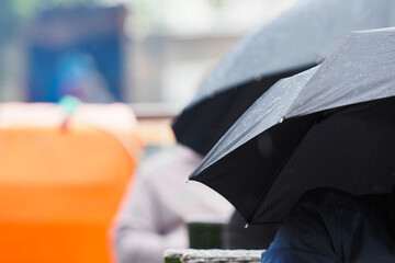 Black umbrellas, people sit outside in the rain