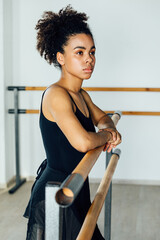 Obraz na płótnie Canvas Portrait of African American ballet dancer standing at barre in studio