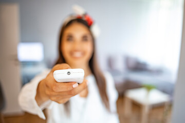 Woman holding remote controller, turning on cooler system air conditioner, setting comfortable...