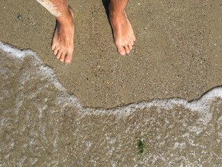 Male feet on the beach on the sand, sunny day, summer