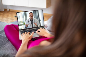Young woman or patient having video chat with doctor on tablet pc computer at home. Woman sitting on the sofa while making video call over laptop with her doctor.