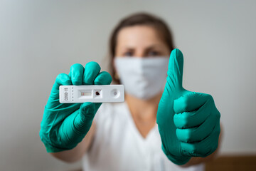 Woman doctor showing negative Covid-19 rapid test wearing green latex gloves - obrazy, fototapety, plakaty