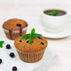 Cupcakes with black currant and mint leaves on a white plate. Selective focus.