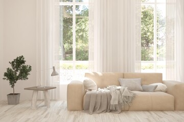 Fototapeta premium White living room with sofa and summer landscape in window. Scandinavian interior design. 3D illustration