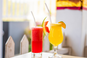 A glass of watermelon juice and orange juice with plastic straw in a restaurant in Bali