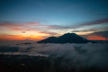 A tranquil landscape view of cloud movement during the morning sunrise with golden sunbeam behind the mountain in Bali