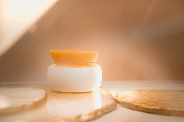 White cosmetic cream jar with orange lid on light pastel color background. Natural minimalism, clean concept. Minimal styling, still life. Beauty blogging, branding layout,  skin care ad mock up