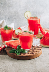 Watermelon lemonade with lime and fresh basil leaves on concrete background. Refreshing summer drink