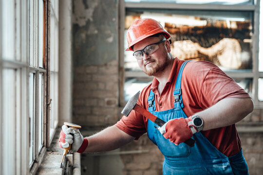 Serious and highly skilled worker handling a brick wall on a large construction site