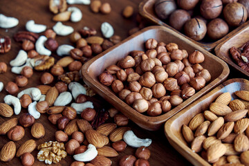 Wooden bowl with mixed nuts on table top view. Healthy food and snack. Walnut, pistachios, almonds, hazelnuts and cashews.