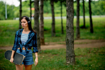 Skater girl holding skateboard and enjoying in music 