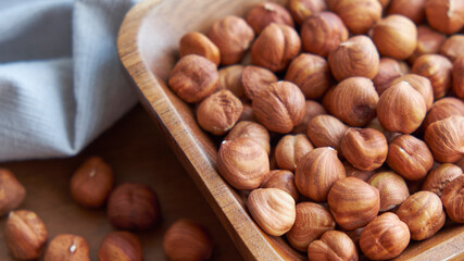 Hazelnut kernels and whole hazelnuts on old brown table, selective focus.
