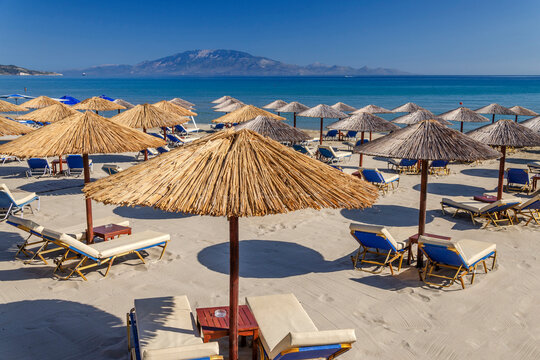 Straw Beach Umbrellas And Sun Chairs On The East Coast Of Zakynthos Island In Greece