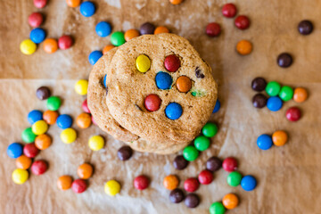 Fototapeta na wymiar Chocolate chip cookie with candy colors on a brown background