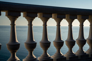 Classic balustrade on the embankment against the sea. White balcony over the sea. Promenade with a beautiful view of the sea on a clear day. Close-up of the balustrade by the sea