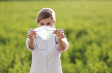 Young woman doctor or nurse showing medical face mask close up