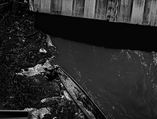 
Aerial of a canoe sitting on a river in black and white