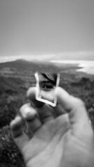 
reflection of an eye in a small mirror and in the background you would see a large dam in black and white
