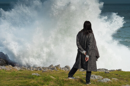 Mujer hispana de mediana edad junto al mar, pensativa mira el horizonte, asturias espa&ntilde;a.