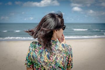 Mujer hispana de mediana edad junto al mar, pensativa mira el horizonte, asturias españa.