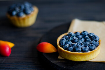 Tart with blueberries and cream on dark wooden table, closeup