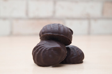 Chocolate-covered marshmallows lie on a wooden table.