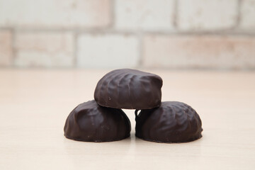 Chocolate-covered marshmallows lie on a wooden table.