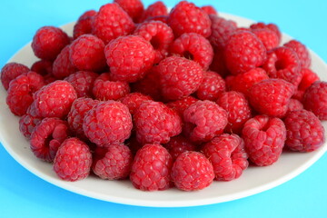 Fresh raspberry on plate close up isolated on light blue background,close up. Summer berries.