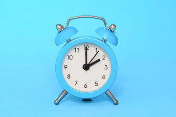 Blue alarm clock on blue background close up. 2 a.m., 2 p.m. Time concept.