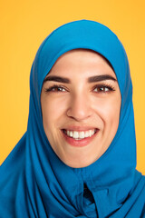 Fototapeta premium Smiling. Close up young muslim woman isolated on yellow studio background. Stylish, trendy. Human emotions, facial expression, sales, ad, shopping concept. Beautiful woman with well-kept skin.