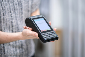 Detail of woman selling with credit card reader using a hygienic and wireless payment terminal.