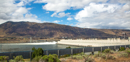 The john day dam on the columbia river near Rufus, Oregon.  Wind power generators are on the skyline of the surrounding hills.
