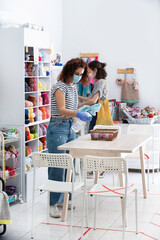 Shop assistant female wearing a hygienic face mask and doing deep cleaning on a small retail store.