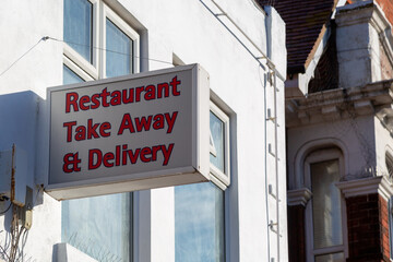 A sign outside a takeaway restaurant stating restaurant takeaway and delivery