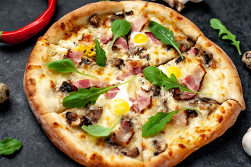 Pizza carbonara with bacon, cheese, mushrooms, quail eggs, creamy sauce on a stone background