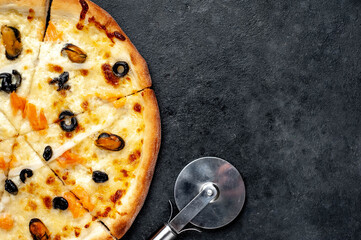 Seafood pizza with salmon, mussels, squid, olives, cheese on a stone background  with copy space for your text