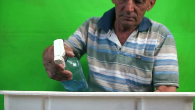 Elderly Caucasian man caring for plants, watering seedlings in a pot, a pensioner taking care of flowers.Selective focus, a man in defocus.Green screen