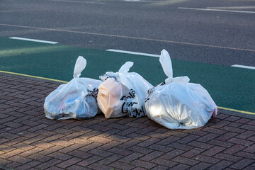 white rubbish bags or trash bags in the street ready for collection