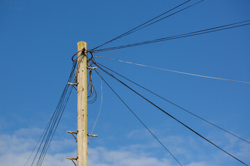 Telephone lines on a wooden pole or telegraph pole in a street heading off to different homes